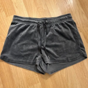 Mörkgrå velourshorts Gina Tricot - Mysiga mörkgrå shorts från Gina Tricot i mjuk velour med snörning i midjan. Perfekta för chill dagar eller när du vill ha något bekvämt och snyggt. Klassisk passform och elastisk midja för extra komfort.🩷