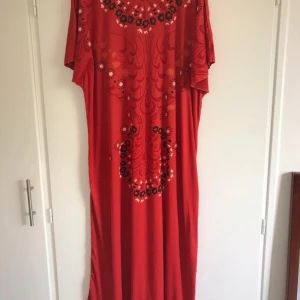 Röd koftan med blommigt mönster - Säljer en röd koftan med blommigt mönster i svart och vitt. Koftanen har lös passform och korta ärmar, perfekt för dig som gillar färg och mönster. Snygg till både vardag och speciella tillfällen.