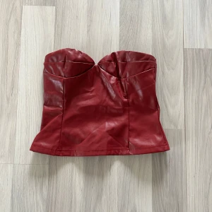 Vinröd tubtopp i skinnimitation - Säljer en vinröd tubtopp i skinnimitation med snygg sweetheart-urringning. Toppen är axelbandslös och har en figurnära passform. Toppen är köpt från shein.