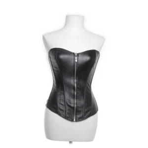Svart korsett  - Snygg svart korsett i skinnimitation med dragkedja framtill och snörning baktill. Aldrig använt, men köpt från Sellpy. Kommer från Bs lingerie
