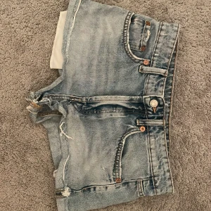Blå jeansshorts med slitna detaljer - Säljer ett par klassiska blå jeansshorts med lågmidja ifrån zara!