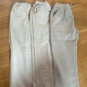 Beiga linnebyxor  - Storlek 152 Använda i gott skick. Paret i mitten sytt några stygn pga hål (se bild 2). Alla par för 400kr