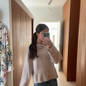 Beige stickad tröja med lös passform - Mysig beige stickad tröja med rund hals och långa ärmar. Tröjan har en avslappnad, lite lös passform och är perfekt att bära till jeans eller kjol. Enkel och stilren design som passar till många tillfällen.