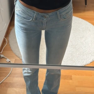 Ljusblå bootcut jeans från Replay - Säljer ett par ljusblå jeans från Replay med bootcut-modell. Jeansen har klassisk femficksdesign, dragkedja och knapp framtill samt normal passform. Perfekta för dig som gillar en tidlös och avslappnad stil.