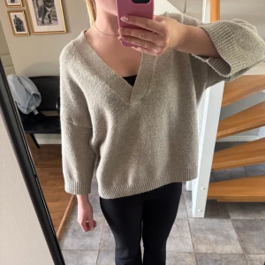 Beige stickad tröja med v-ringning -  beige stickad tröja med djup v-ringning och trekvartsärmar. fåtal gånger använd. nypris 600kr