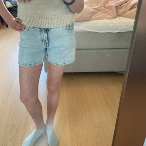 Ljusblå jeansshorts från Lindex - Ljusblå jeansshorts från Lindex med klassisk femficksdesign och knappgylf. Shortsen har en rak passform och är tillverkade i denim. Perfekta för varma dagar och enkla att matcha med olika toppar.