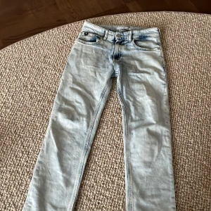 Calvin Klein jeans - Säljer ett par ljusblå jeans från Calvin Klein Jeans med klassisk femficksdesign och diskret CK-logga på bakfickan. Jeansen har normal passform och raka ben, perfekta till vardagslooken.