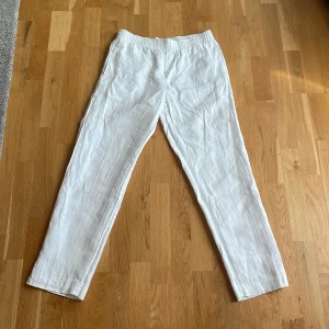 Vita linnebyxor från H&M - Säljer ett par vita linnebyxor från H&M med resår i midjan och regular fit. Byxorna har raka ben och är tillverkade i ett tunt, luftigt material som passar perfekt till varmare dagar.