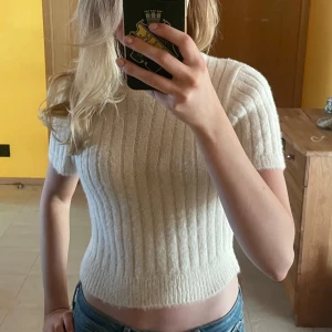 Vit ribbad croppad stickad tröja från Zara - Säljer en vit, croppad stickad tröja från Zara. Tröjan har korta ärmar och är ribbstickad vilket ger en snygg struktur. Perfekt till jeans eller kjol.