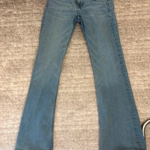 Ljusblå bootcut jeans lowwaist  - Säljer ett par ljusblå bootcut jeans med klassisk femficksdesign och dragkedja. Jeansen har normal passform och är tillverkade i denim. Perfekta för dig som gillar en retroinspirerad look med utsvängda ben.