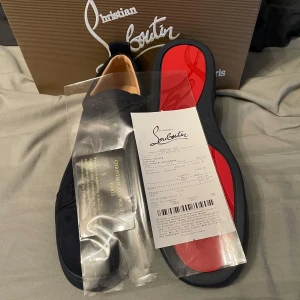 Mörk blåa sneakers från Christian Louboutin - Säljer ett par mörkblåa  sneakers från Christian Louboutin med klassisk röd sula. Skorna har snörning och är tillverkade i mocka. Perfekta för dig som vill ha en stilren och lyxig look.