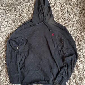 Svart hoodie från Ralph Lauren - Säljer en riktigt fet svart hoodie från Ralph Lauren med röd logga. Nypris=1200, mitt pris endast 400,skick 9/10. Perfekt för sommaren.                                             Är i storlek S men kan även passa M.                  Har endast en pytteliten defekt men det märks inte om man inte kollar riktigt ordentligt.