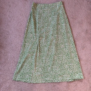Grön blommig kjol - Snygg grön kjol men en slits fram. I storlek XS. Endast använd en gång och som ny. Färgen ser lite missvisande ut på de första bilderna, kolla sista bilden för en mer korrekt bild av färgen. Superfin men kommer inte till användning. ❤️ 