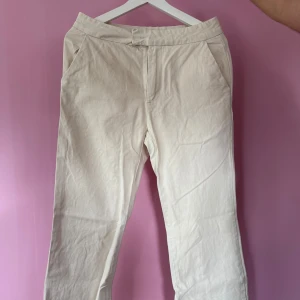 Beiga raka byxor i bomull - Säljer ett par beiga byxor med raka ben och normal passform. Byxorna har fickor framtill och är tillverkade i ett mjukt bomullsmaterial. Perfekta för en avslappnad och stilren look.