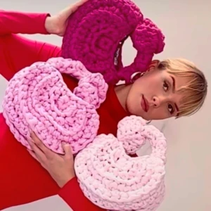 Handvirkad rosa axelväska - Supergullig handvirkad axelväska i ljusrosa med chunky garn och rund form. Väskan har ett tjockt handtag och är perfekt för att addera en söt touch till din outfit. Passar dig som gillar unika accessoarer och pastellfärger.
