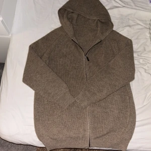 Beige stickad hoodie med dragkedja - Jag säljer en helt oanvänd stickad beige kofta då den var förstor. Storleken på koftan är S men den är lite större i modellen och skulle säga att den är lite mer som en m. Den har en dragkedja som går hela vägen ner.