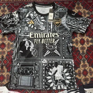 Arsenal svartvit fotbollströja från Adidas - Unik svartvit Arsenal fotbollströja från Adidas med grafiskt mönster och gulddetaljer. Tröjan har korta ärmar, klubbmärke och Adidas-logga på bröstet samt Emirates Fly Better-tryck framtill. Perfekt för dig som vill sticka ut på läktaren eller planen.Storleken på tröjan är S, De är helt nya passa på köp, du kan även beställa andra fotbollströjor av oss de ba o skriva privat till oss så löser vi, köparen står för frakten.