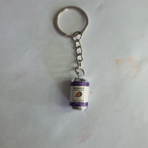 Nyckelring med ciderburk lila - Säljer en unik nyckelring med en miniatyr av en Rekorderlig ciderburk i lila och vitt. Perfekt accessoar för dig som gillar detaljer med en twist. Metallkedja och ring för enkel fastsättning på nycklar eller väska.