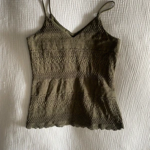 Linne - Säljer ett grönt linne från Vero Moda med smala axelband och v-ringning. Toppen är täckt av vacker spets och har en feminin, croppad passform. Perfekt för sommardagar eller som lager på lager-plagg.