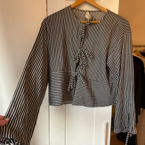 Blus med knyte  - Superfin randig blus med knyte, även vid de vida armarna. Står tyvärr ingen storlek men skulle själv uppskatta till en storlek S. Använd enstaka gång.