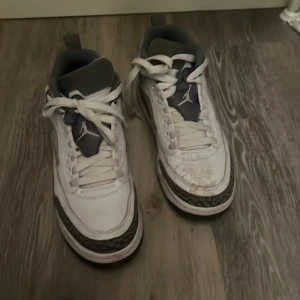 Vita Nike Air Jordans sneakers.fötlåt för alla fläckar jag ska tvätta de  - Säljer ett par klassiska vita Nike Air Jordans sneakers med grå och svarta detaljer samt mönstrad sula. Skorna har snörning och rund tå, perfekt för dig som gillar streetwear och sportig stil.