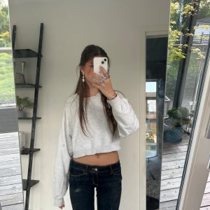 Grå croppad sweatshirt - Säljer en ljusgrå superfin croppad sweatshirt med långa ärmar från H&M. Tröjan har en avslappnad passform och är perfekt för en chill vardagslook. Enkel och stilren design utan synliga loggor eller detaljer.