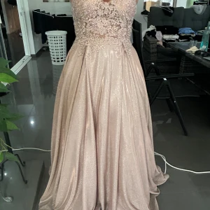 Champagnefärgad långklänning med spets och glittrig kjol - Säljer denna fantastiska balklänning/festklänning i ljusrosa med glitter, perfekt för bal, gala eller fest! Klänningen har en fin urringning, figurnära liv och en vid kjol som faller vackert. Väldigt bekväm att ha på sig och ger en riktigt lyxig känsla. Använd endast en gång.  💎 Storlek: 36/38 💰 Pris: 3000 kr (kan diskuteras vid snabb affär) 📍Finns i Norrköping  Skicka gärna ett meddelande vid intresse eller fler bilder! 💌 