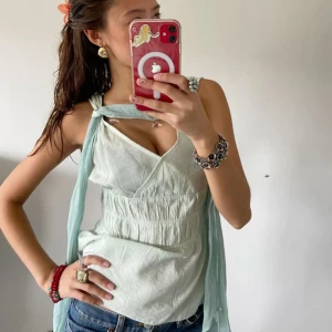 Ljusgrön omlottopp - Säljer en ljusgrön omlottopp med knytband vid axlarna. Toppen har en v-ringad design och är ärmlös, vilket gör den perfekt för varmare dagar. Materialet ser luftigt och bekvämt ut. Har inget märke på sig eller storleks tag men den är lite Förstor för mig som har xs/s men skulle tippa att den passar s/m💘