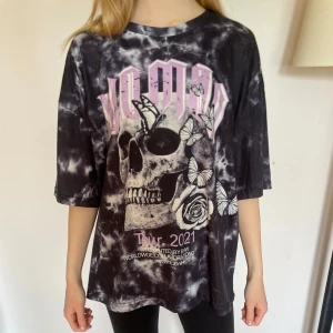 Svart och vit tie-dye t-shirt med dödskalletryck - Oversized t-shirt i svart och vit tie-dye med stort tryck av dödskalle, fjärilar och rosor framtill. Texten 'Tour 2021' och rosa detaljer. Perfekt för halloween💀