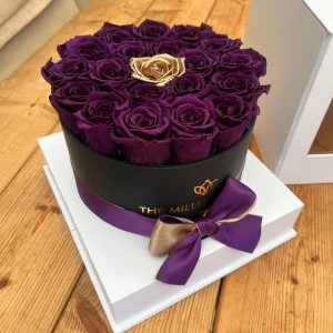 Rund ask med lila och guldiga rosor från The Million Roses - The Million Roses box. Lyxig rund ask fylld med mörklila rosor och en ros i guld i mitten. Asken är svart med lila och guldigt band och levereras i en vit presentbox med fönster. Perfekt som exklusiv accessoar eller present. Inga synliga defekter, endast den vita förvaringslådans undersida har små märken från att ha stått på en hylla. Kan mötas upp för avhämtning. Pris kan diskuteras 🫶