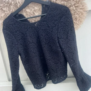 Svart spetsstickad tröja  - Säljer en svart spetsstickad tröja från Zara Woman. Tröjan har lång ärm, vackert hålmönster och lätt utsvängda ärmslut. Den ger en elegant touch till din outfit. SKRIV INNAN KÖP!❤️