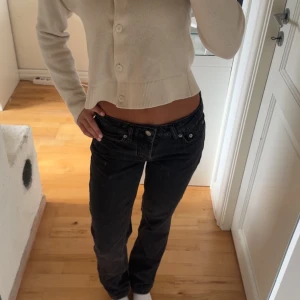 Svarta lågmidjade jeansbyxor - Säljer ett par svarta jeans med låg midja och raka ben. Klassisk femficksmodell med knappar och dragkedja framtill. 