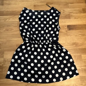 Svart prickig klänning från Amisu - Snygg svart klänning med vita prickar från Amisu. Den har en elastisk midja som ger en fin passform och är ärmlös för en luftig känsla. Perfekt för en somrig look! Storlek L (42) men passar nog alla storlekar under också, bra för en layerd look 👀 