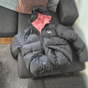 Svart pufferjacka från Stussy - Pris går att diskuteras våga fråga. Säljer en svart pufferjacka från Stussy med rosa foder och dragkedja.  stussy micro ripstop down parka, är 185 passar skit bra