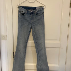 Blå bootcut jeans från Vero Moda - Säljer ett par ljusblå bootcut jeans från Vero Moda. Jeansen har klassisk femficksdesign, hög midja och lätt utsvängda ben. Tillverkade i denim med en snygg tvätt och diskreta slitningar för en trendig look.