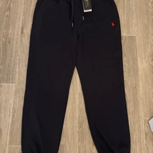 Mörk blå mjukisbyxor från Polo Ralph Lauren - NYA kostar ungefär 1,9 mitt.Helt NYA  Snygga mörk blå mjukisbyxor från Polo Ralph Lauren med dragsko i midjan och den klassiska röda loggan broderad på ena benet. Perfekta för en avslappnad stil och riktigt sköna att ha på sig.