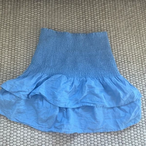 Blå volangkjol från mango - Supersöt blå kjol från mango med smock i midjan och dubbla volanger. Kjolen är kort och är i typ linne tyg. Strl xs men stretchig så passar nog S/M också🩷 endast använd enstaka gånger 