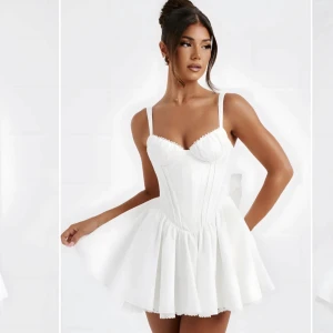 Vit kort klänning med volangdetaljer - Snygg vit kort klänning med smala axelband och volangdetaljer. Klänningen har en åtsittande överdel med en markerad midja och en utsvängd kjol. Perfekt för sommarens fester! Den har inte använt en enda gång!