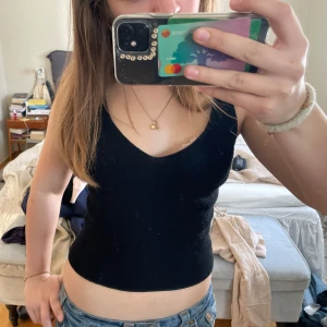 Svart ribbad linnetopp från Bik Bok - Säljer en stilren svart ribbad/stickad linnetopp från Bik Bok. Toppen har en v-ringad design och är ärmlös, vilket gör den perfekt för varmare dagar. Passar bra till både jeans och kjol. Hör av dig vid intresse!