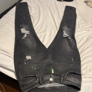 Svarta jeans från Dsquared2 - Snygga svarta jeans från Dsquared2 med slitna detaljer och färgstänk. De har en klassisk femficksdesign och en knappgylf. Perfekta för en trendig look. Pris kan diskuteras 