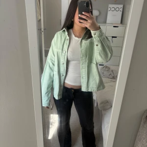 Ljusgrön jeansjacka - Säljer en ljusgrön jeansjacka med knappar framtill. Jackan har en avslappnad passform och långa ärmar. Perfekt för vår och sommar!