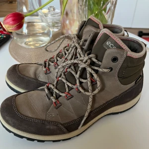 Grå och bruna kängor från Ecco stl 37 - Säljer ett par robusta kängor från Ecco i grått och brunt med Gore-Tex för vattentäthet. Skorna har snörning och en slitstark sula med bra grepp. Perfekta för utomhusaktiviteter och håller fötterna torra och bekväma.