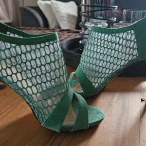 Gröna klackskor med nätmönster - Snygga gröna klackskor med ett unikt nätmönster och öppen tå. Skorna har en dragkedja baktill för enkel på- och avtagning. Perfekta för att ge en färgklick till din outfit. Står  stl 38 men jag har 39 och dem passar mig perfekt 