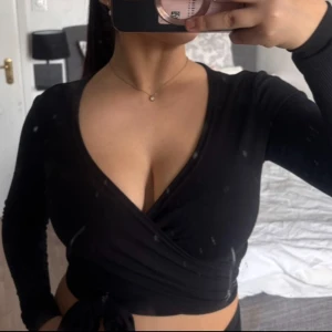 Svart topp - Snygg svart långärmad topp med knytning i midjan. Den har använts men är i mycket bra skick.