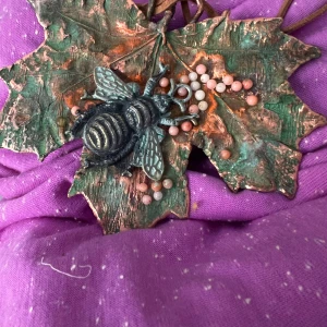 Halsband med löv och torkade blommor - Unikt halsband med stort lövformat hänge i metall och två torkade blommor på framsidan. Hänget har en rustik, antik finish i grönt och koppar. Hängs i ett brunt läderband.