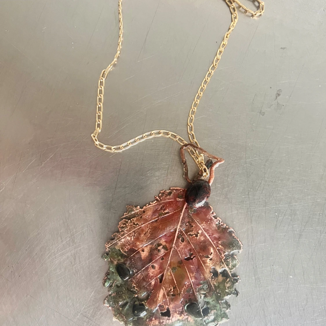 Halsband med lövformat hänge i metall