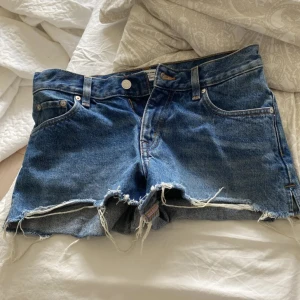 Blå lågmidjade jeansshorts från & Other Stories - Säljer ett par klassiska blå lågmidjade jeansshorts från & Other Stories. De har råa, fransiga benslut och femficksmodell. Shortsen är högmidjade och har en avslappnad passform. Perfekta för sommaren! Midjemått 37❤️