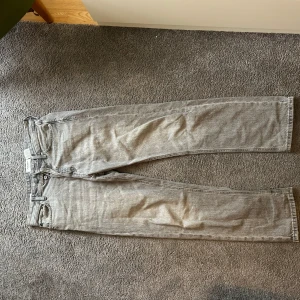 Grå jeansbyxor  - Säljer ett par grå jeansbyxor från Levi's med klassisk femficksdesign och raka ben. Byxorna har knappgylf och bälteshällor. Perfekta för en avslappnad stil.