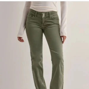 Gröna Nelly jeans - Snygga olivgröna jeans med bootcut passform och hög midja. Byxorna har klassiska fem fickor, bälteshällor och stängs med dragkedja och två knappar. Perfekta för dig som vill ha en stilren och trendig look. Använda 1 gång! Säljer ändast för bra pris