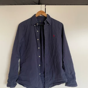 Mörkblå skjorta från Ralph Lauren - Klassisk mörkblå skjorta från Ralph Lauren med slim fit-passform. Storlek M, och sparsamt använd